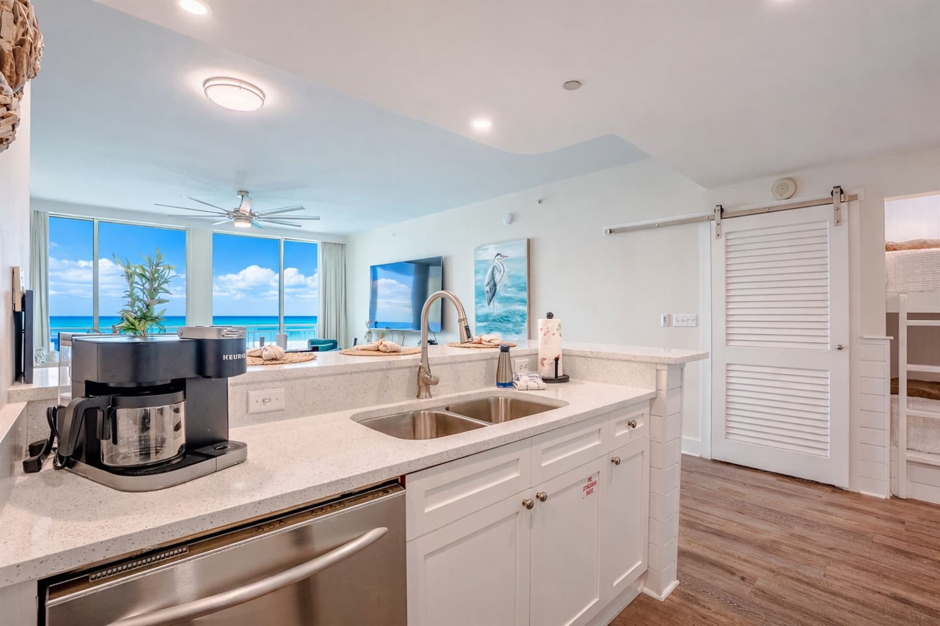 Kitchen with coffee maker, stainless sink, and gulf view through to living area